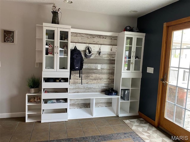 mudroom featuring tile patterned flooring, baseboards, and a textured ceiling