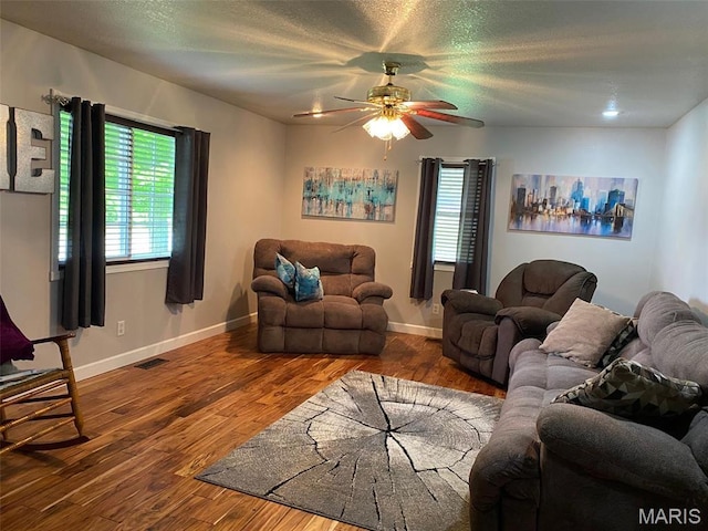 living area featuring healthy amount of natural light, wood finished floors, a ceiling fan, and a textured ceiling
