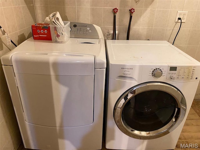 washroom with tile walls and washing machine and dryer