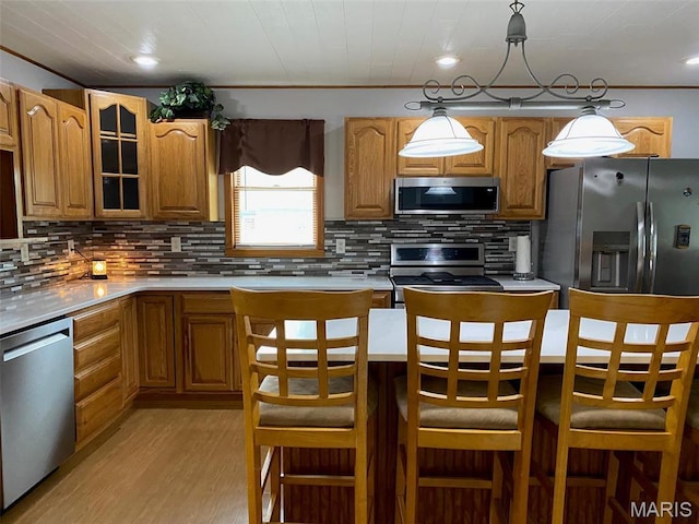 kitchen featuring appliances with stainless steel finishes, light wood finished floors, backsplash, light countertops, and crown molding