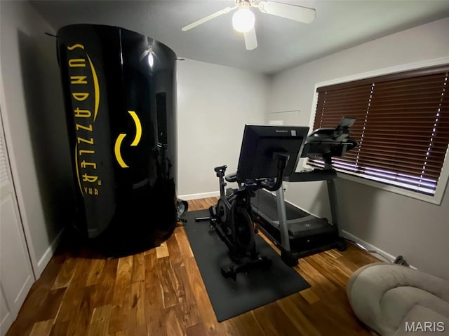 exercise area featuring a ceiling fan, wood finished floors, and baseboards