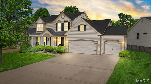 traditional home featuring a garage, driveway, a yard, and roof with shingles
