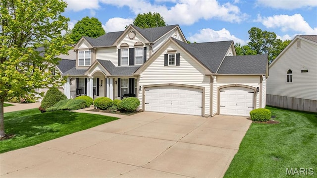 traditional home featuring a front lawn, concrete driveway, an attached garage, and a shingled roof