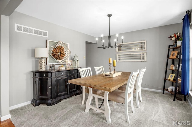 dining space with a chandelier, baseboards, and light carpet