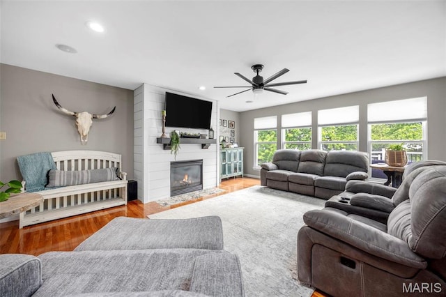 living room with a ceiling fan, wood finished floors, a large fireplace, and recessed lighting