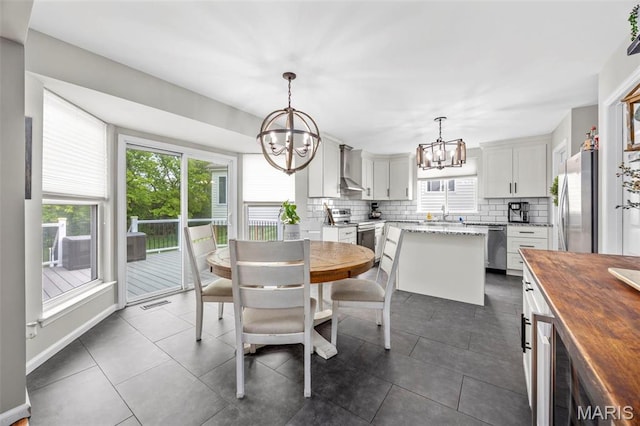 dining room featuring a chandelier, plenty of natural light, and dark tile patterned floors