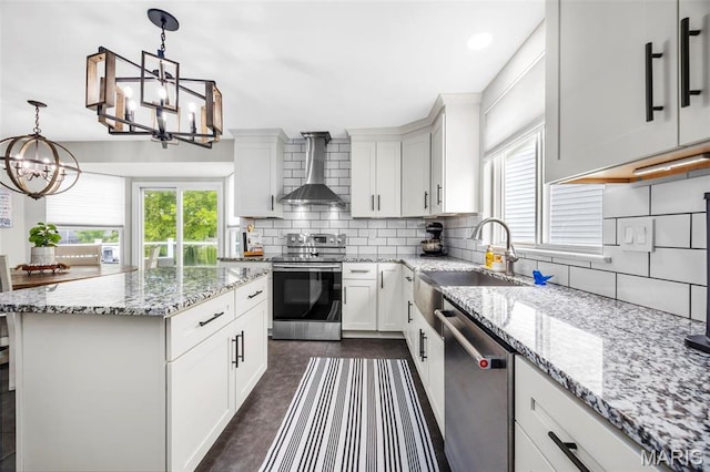 kitchen featuring stainless steel appliances, a chandelier, wall chimney exhaust hood, a sink, and healthy amount of natural light