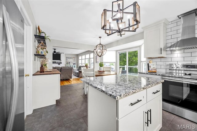 kitchen with stainless steel appliances, a chandelier, dark tile patterned flooring, tasteful backsplash, and a center island