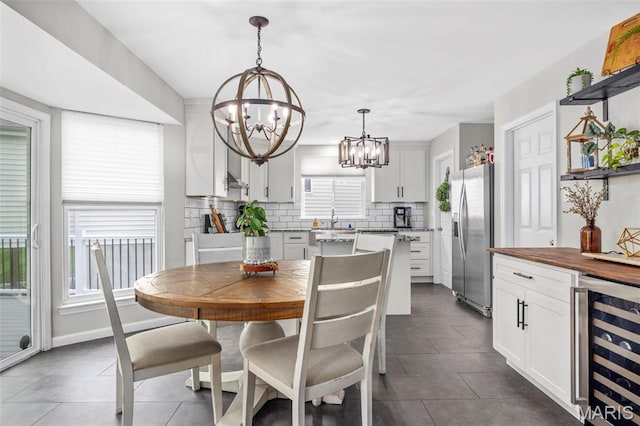 dining room featuring beverage cooler, a chandelier, and dark tile patterned flooring
