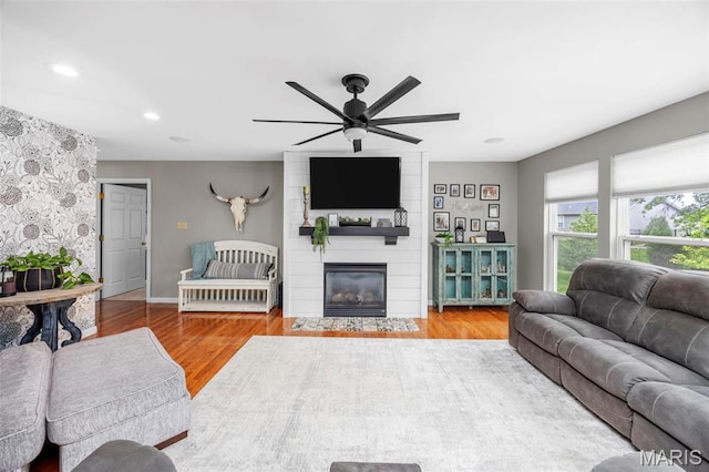living room featuring a ceiling fan, wood finished floors, a large fireplace, recessed lighting, and baseboards