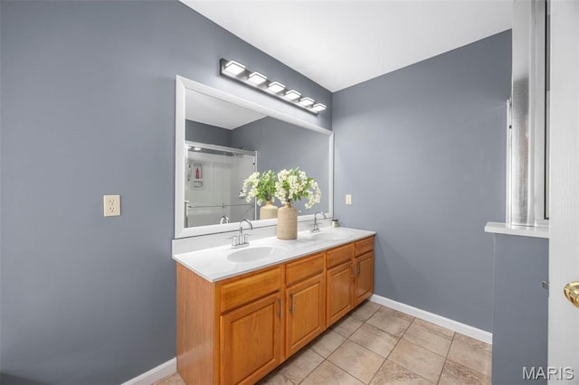 full bath with a shower with shower door, tile patterned floors, double vanity, and baseboards