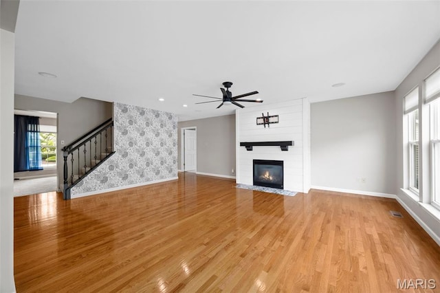 12 Lambeth Ln Unit 11B, Dardenne Prairie, MO 63368 - unfurnished living room featuring baseboards, light wood-style flooring, ceiling fan, stairs, and a large fireplace