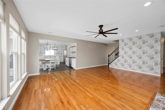 12 Lambeth Ln Unit 11B, Dardenne Prairie, MO 63368 - unfurnished living room with stairs, wood finished floors, ceiling fan, baseboards, and a chandelier
