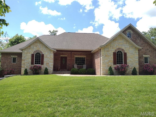 24473 Remington, Lebanon, MO 65536 - french country inspired facade featuring stone siding, a front lawn, a shingled roof, and brick siding