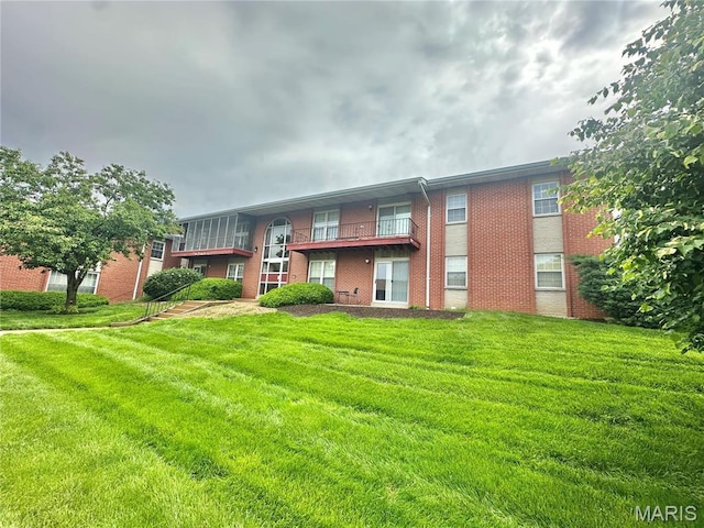 back of property with brick siding and a lawn