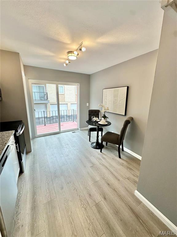 sitting room featuring baseboards, light wood-style floors, and a textured ceiling