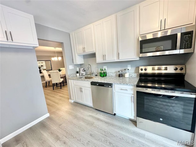 kitchen featuring appliances with stainless steel finishes, a sink, light wood-style flooring, and white cabinetry