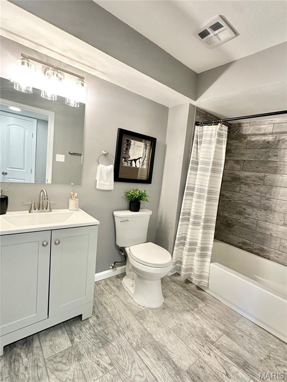 full bathroom with toilet, baseboards, shower / bathtub combination with curtain, and vanity
