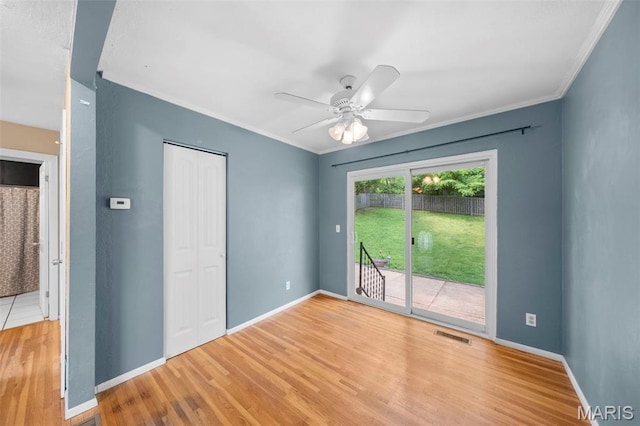empty room with wood finished floors, baseboards, a ceiling fan, and crown molding