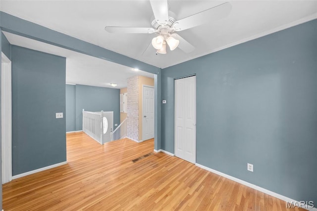 empty room with baseboards, wood finished floors, and ceiling fan