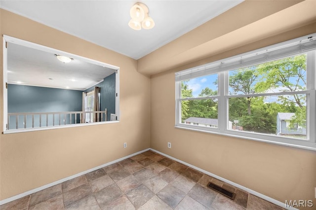 spare room featuring baseboards and stone finish floors