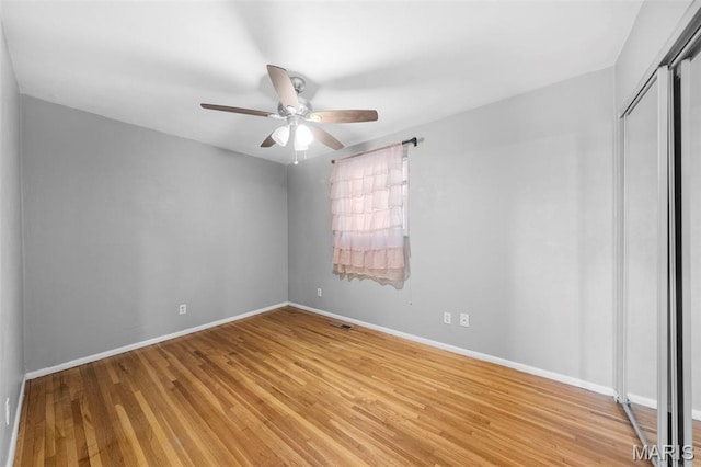 unfurnished bedroom with baseboards, light wood-style floors, a closet, and a ceiling fan