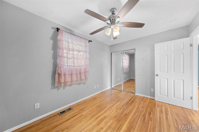 unfurnished bedroom with wood finished floors, a closet, baseboards, and ceiling fan
