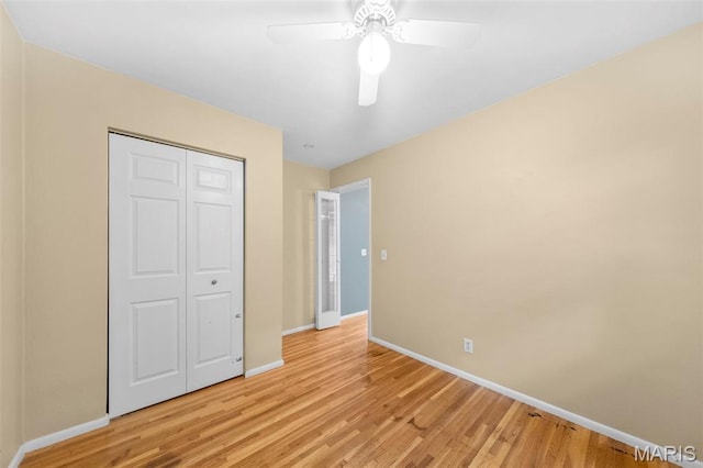 unfurnished bedroom with baseboards, light wood-style floors, a closet, and a ceiling fan