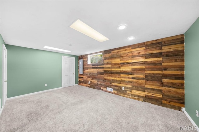 carpeted spare room featuring wooden walls, baseboards, and recessed lighting