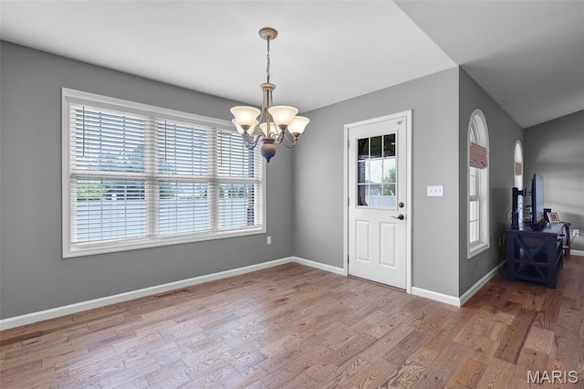 entrance foyer with a chandelier, wood finished floors, and baseboards