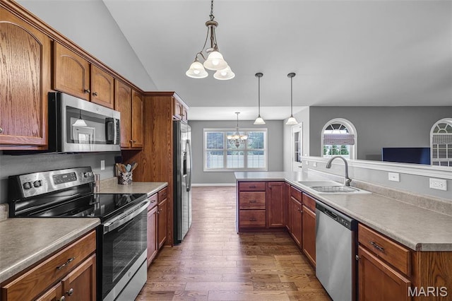 kitchen with appliances with stainless steel finishes, a chandelier, dark wood-style flooring, a sink, and hanging light fixtures