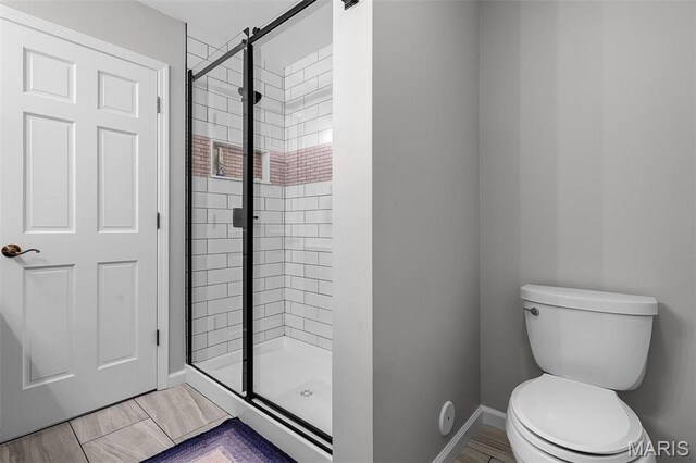 bathroom featuring a shower stall, baseboards, and toilet