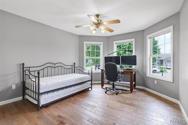 bedroom with wood finished floors, baseboards, and a desk