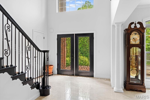 foyer with decorative columns, stairway, french doors, baseboards, and a high ceiling