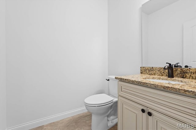 half bath with vanity, toilet, and baseboards