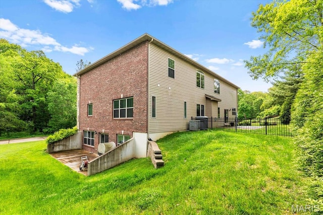 rear view of house featuring brick siding and central AC