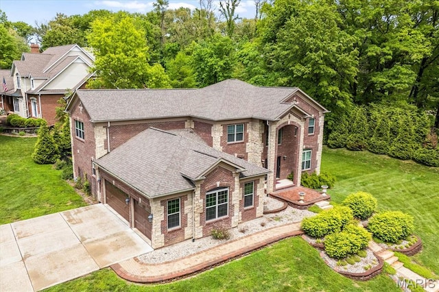 traditional-style home featuring brick siding, concrete driveway, a front yard, and an attached garage