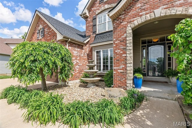 entrance to property with brick siding and roof with shingles
