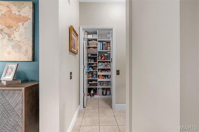 hall with light tile patterned flooring and baseboards