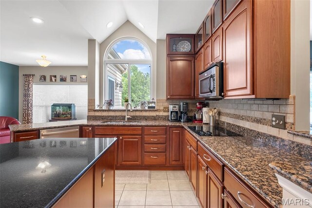 kitchen with a sink, stainless steel appliances, lofted ceiling, light tile patterned flooring, and decorative backsplash