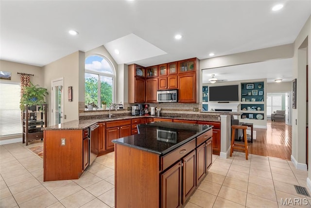 kitchen featuring appliances with stainless steel finishes, a peninsula, a kitchen island, a sink, and a ceiling fan