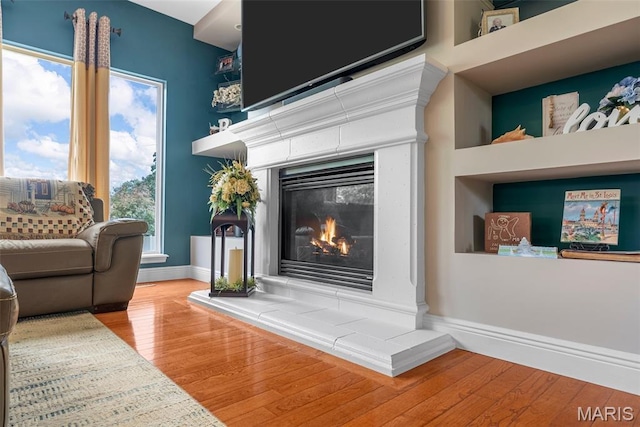 living area featuring a fireplace, wood finished floors, and baseboards