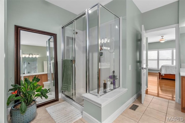 ensuite bathroom featuring tile patterned flooring, a shower stall, and baseboards