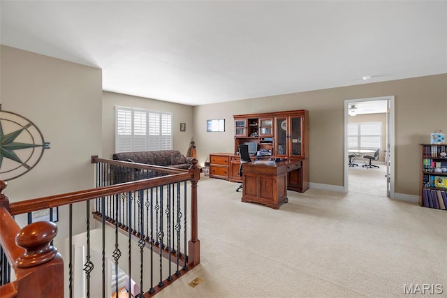 corridor with light carpet, baseboards, an upstairs landing, and an office area