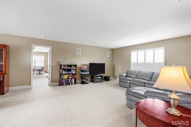 carpeted living area with healthy amount of natural light and baseboards