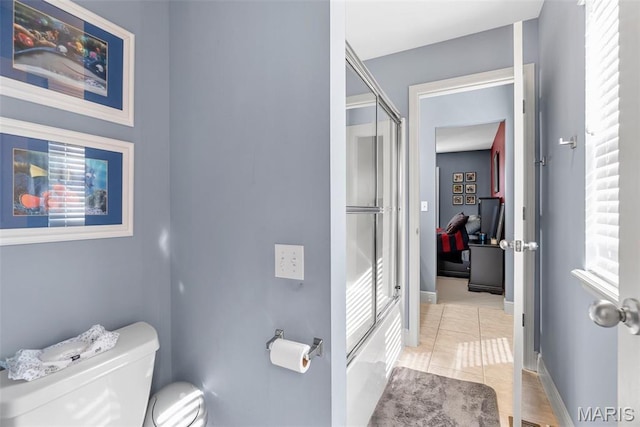 bathroom with a shower with door, toilet, tile patterned floors, and baseboards