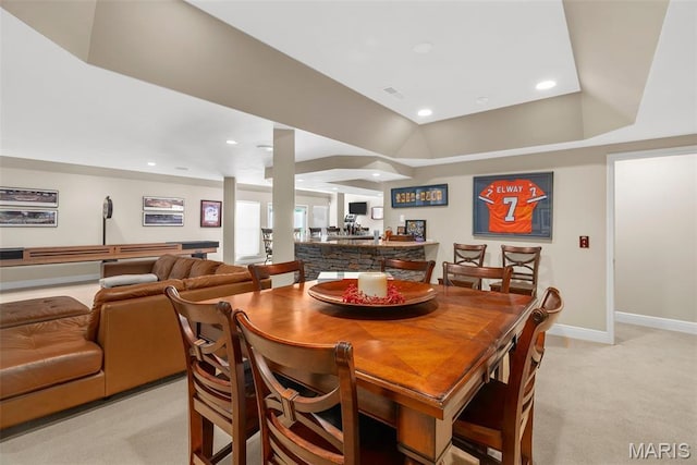 dining area with light colored carpet, baseboards, a raised ceiling, and recessed lighting