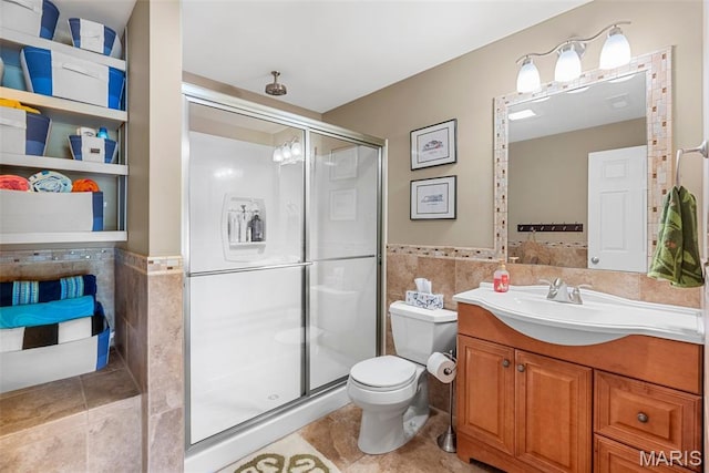 full bathroom with tile walls, a shower stall, vanity, toilet, and tile patterned floors