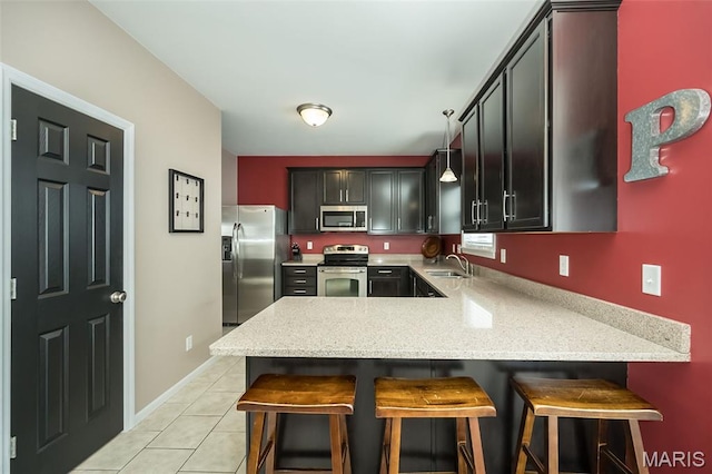 1119 Maywood Dr, Eureka, MO 63025 - kitchen featuring appliances with stainless steel finishes, a peninsula, light tile patterned floors, and a kitchen breakfast bar