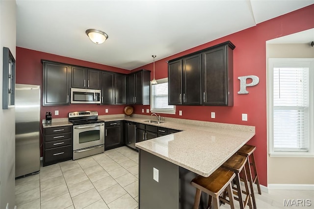1119 Maywood Dr, Eureka, MO 63025 - kitchen featuring stainless steel appliances, a peninsula, light stone countertops, a breakfast bar, and pendant lighting
